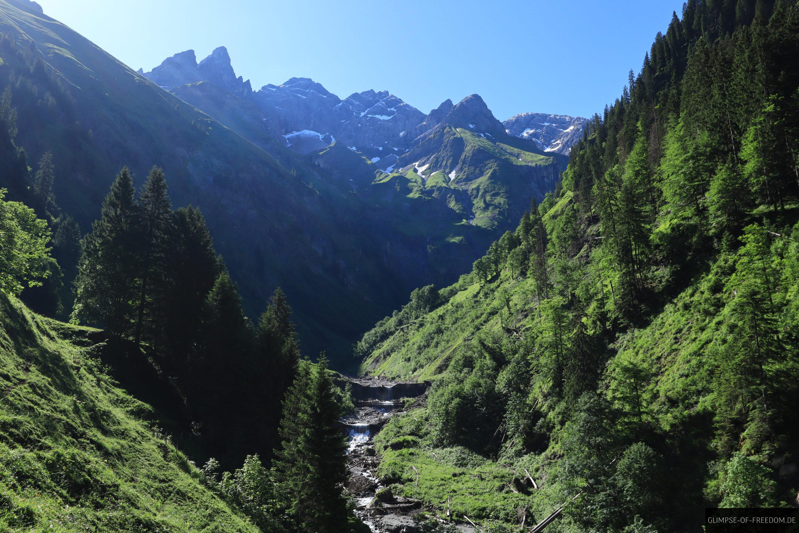Blick ueber Bachlauf und Wasserfall auf die Berge scaled Blick über Bachlauf und Wasserfall auf die Berge