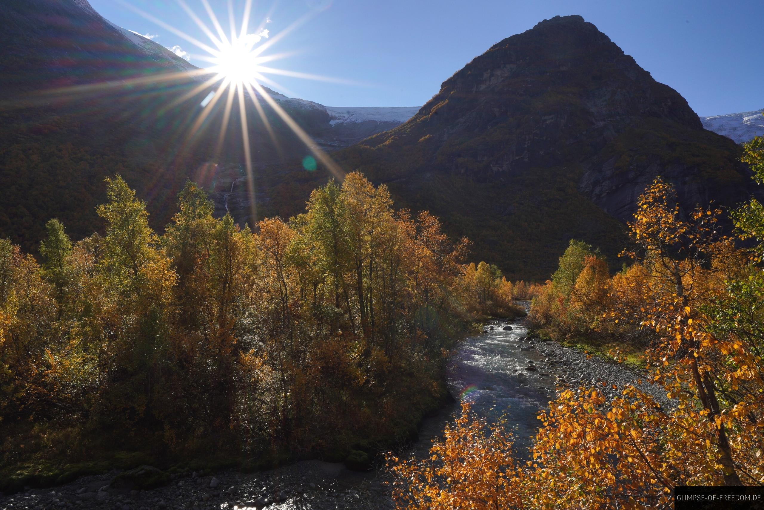 Flusslauf mit Gletscher und Sonne am Berg Flusslauf mit Gletscher und Sonne am Berg