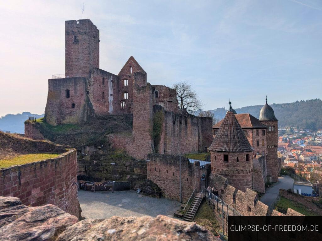 Burg Wertheim Ansicht. Mittelalterliche Burgruine mit Turm und Stadt im Hintergrund. Rotes Sandsteinmauerwerk.