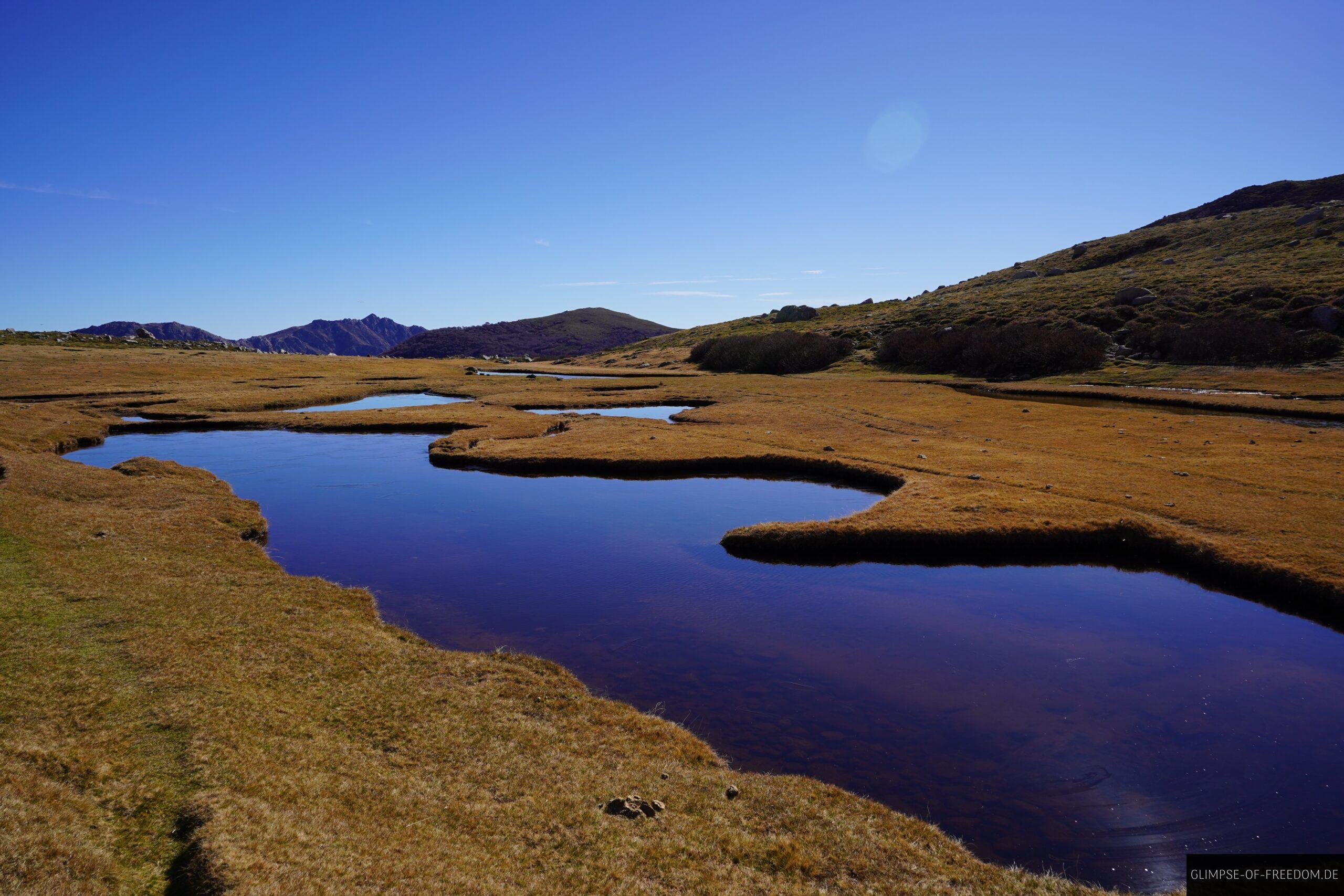 korsika pozzi moorlandschaft bergpanorama wanderung scaled Korsika Pozzi Moorlandschaft mit Wasserflächen und Bergpanorama unter blauem Himmel.
