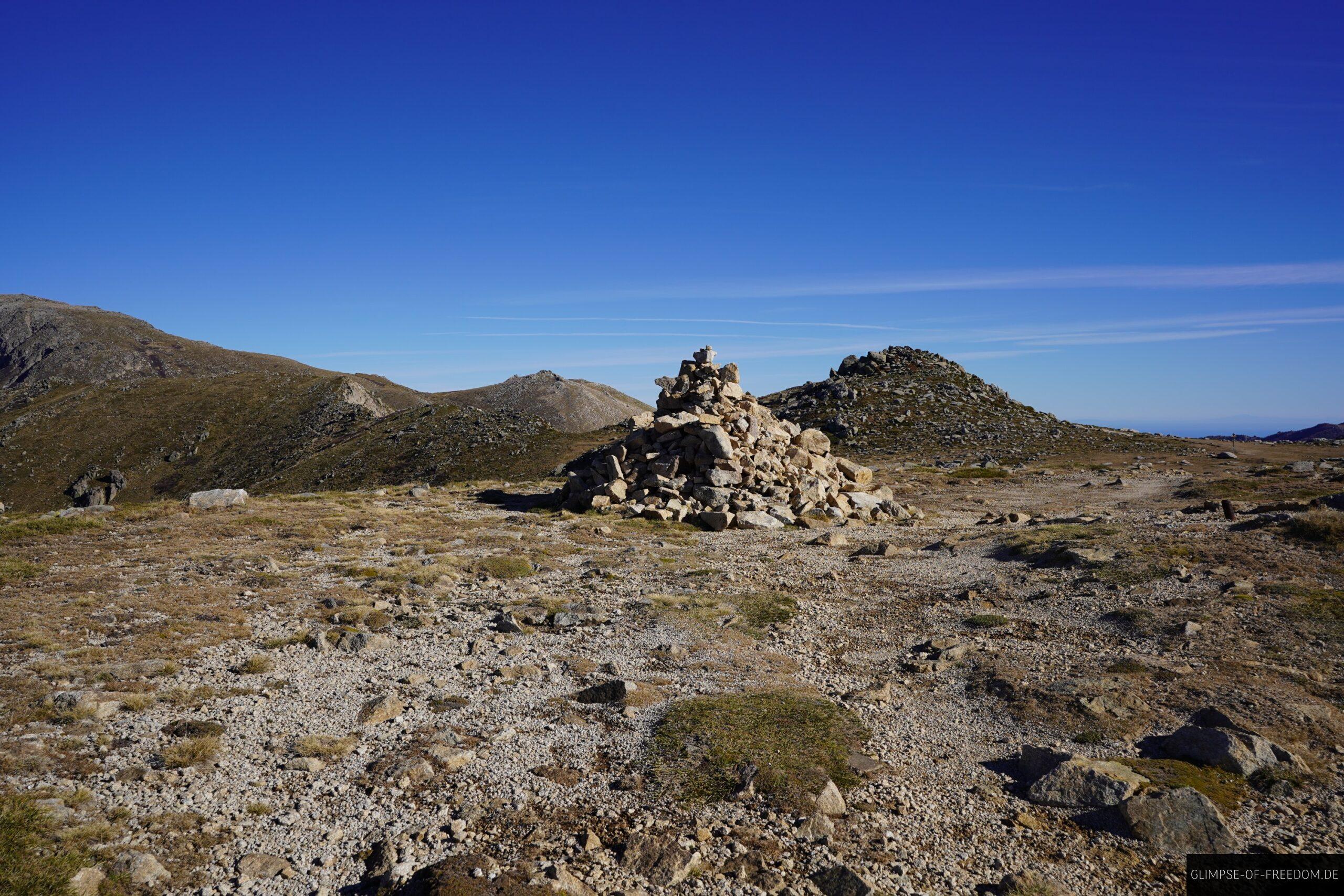 steinmann korsika wanderung bergpanorama scaled Steinmann auf Korsika Wanderung mit Bergpanorama unter blauem Himmel.
