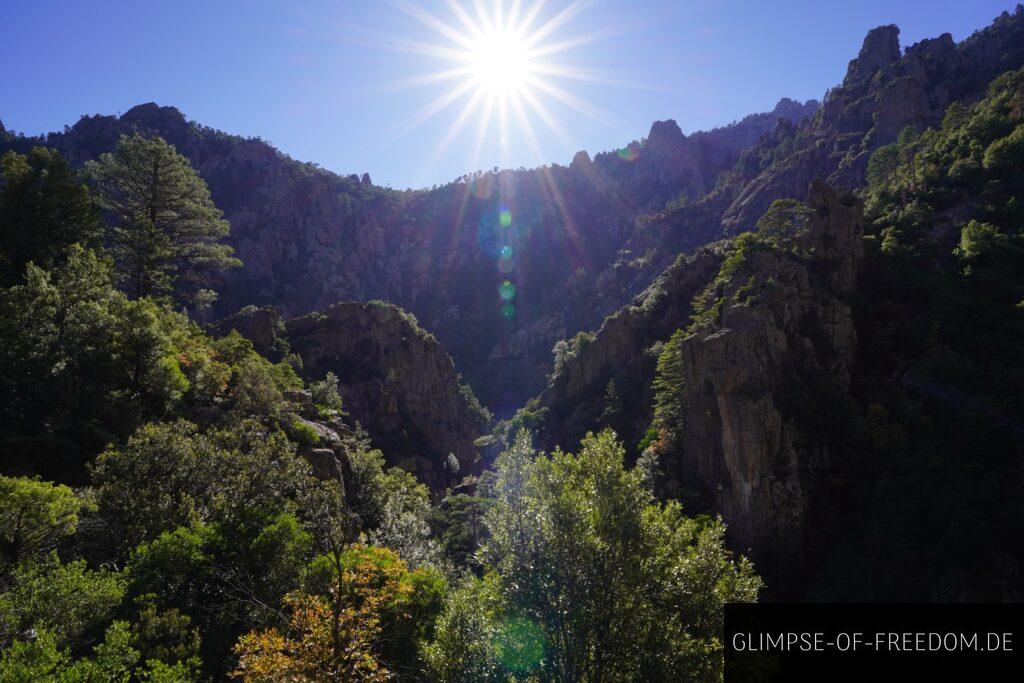 Sonne über der Tavignano Schlucht auf Korsika mit Felsen und Bäumen.