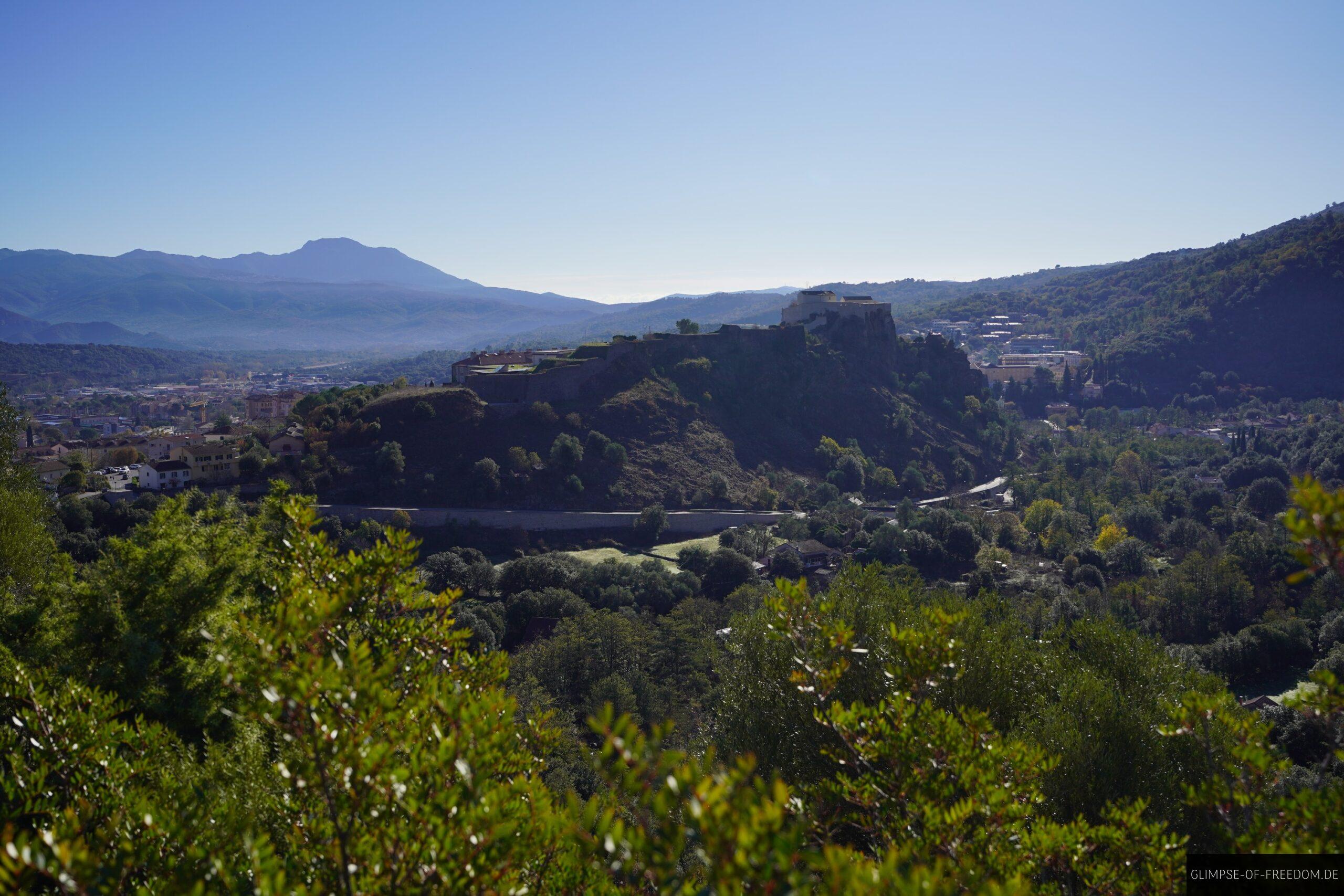 zitadelle corte korsika berglandschaft scaled Zitadelle von Corte auf Korsika, eingebettet in grüne Hügel und mit Bergen im Hintergrund unter blauem Himmel.